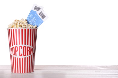 Delicious popcorn with tickets on wooden table against white background