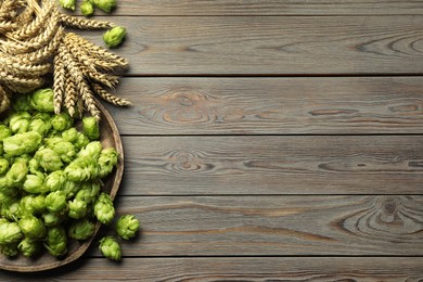 Tray with fresh green hops and wheat ears on wooden table, flat lay. Space for text