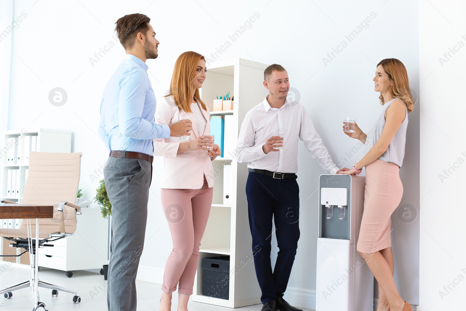 Photo of Co-workers having break near water cooler at workplace