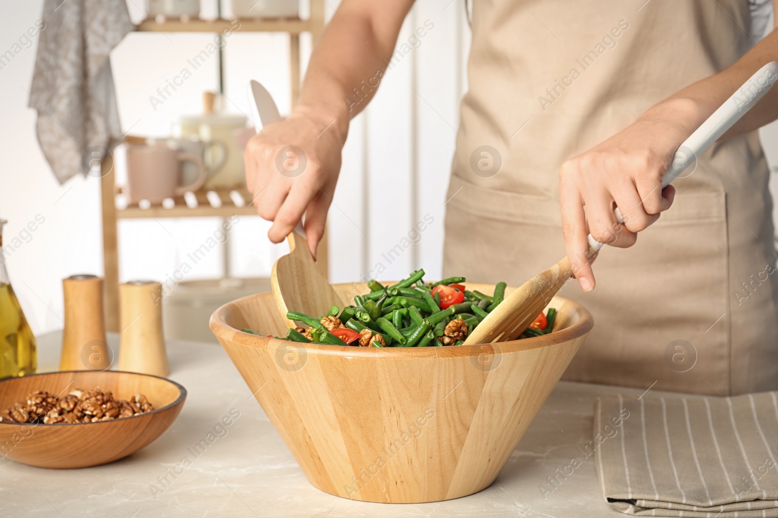 Photo of Woman preparing healthy salad with green beans, cherry tomatoes and walnuts at table