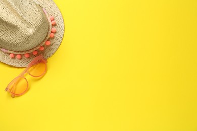 Photo of Hat and sunglasses on yellow background, flat lay with space for text. Sun protection accessories