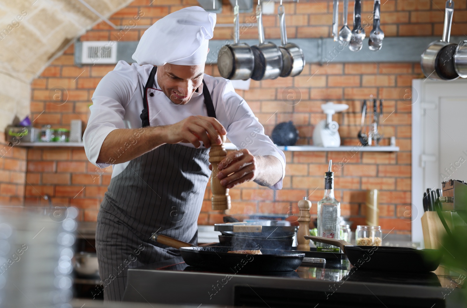 Photo of Professional chef cooking meat on stove in restaurant kitchen