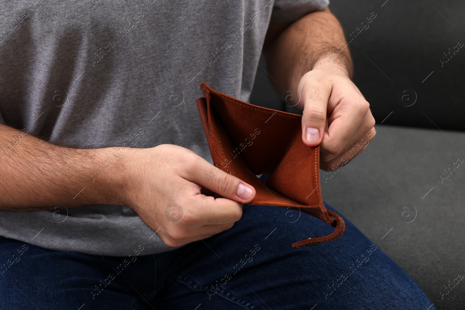 Photo of Man with empty wallet on sofa, closeup