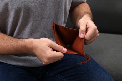 Photo of Man with empty wallet on sofa, closeup