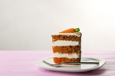 Photo of Sweet carrot cake with delicious cream on pink wooden table against light background. Space for text