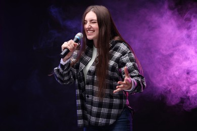 Emotional woman with microphone singing in color lights