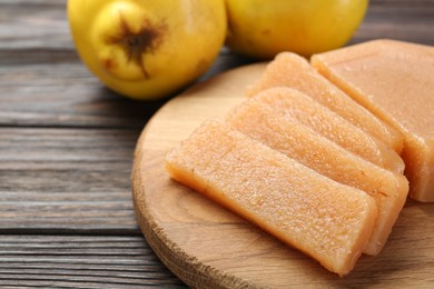 Photo of Tasty sweet quince paste and fresh fruits on wooden table, closeup. Space for text