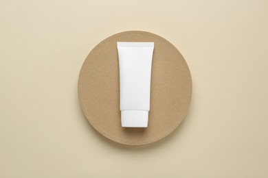 Photo of Tube of hand cream on beige background, top view