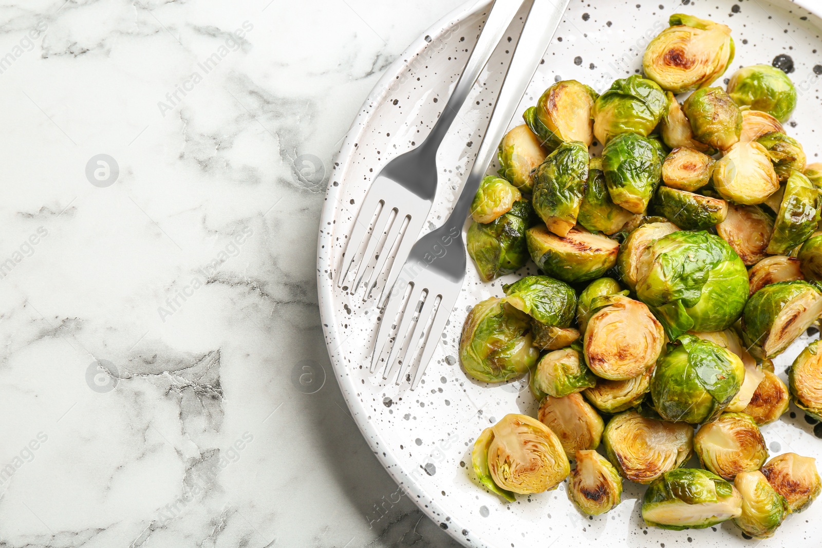 Photo of Delicious roasted brussels sprouts on white marble table, top view. Space for text