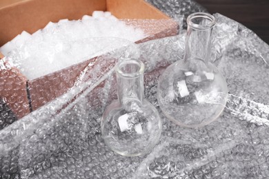 Photo of Flasks with bubble wrap and cardboard box on table