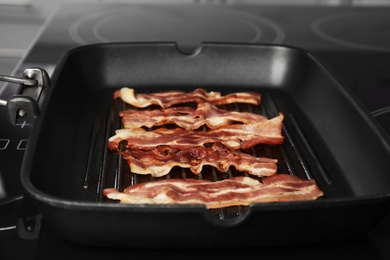 Slices of tasty fried bacon in grill pan indoors