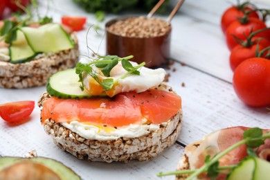 Photo of Crunchy buckwheat cakes with salmon, poached egg and microgreens on white wooden table, closeup