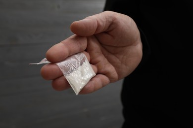 Drug addiction. Man with plastic bag of cocaine on grey background, closeup