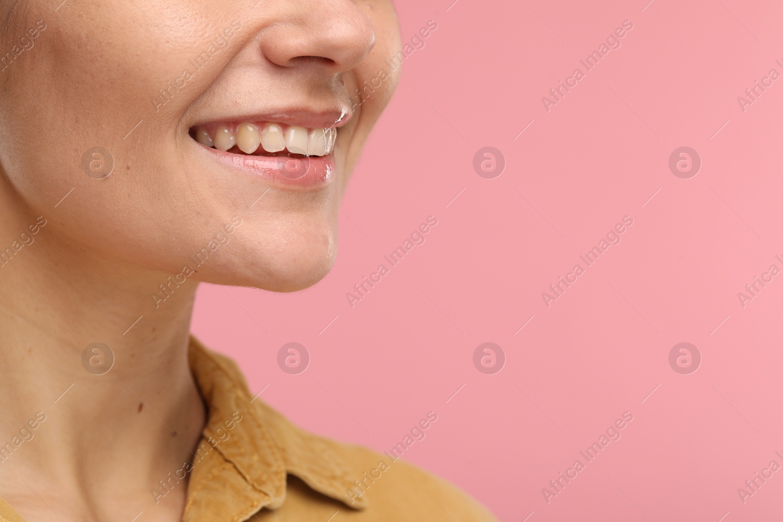 Photo of Woman with clean teeth smiling on pink background, closeup. Space for text