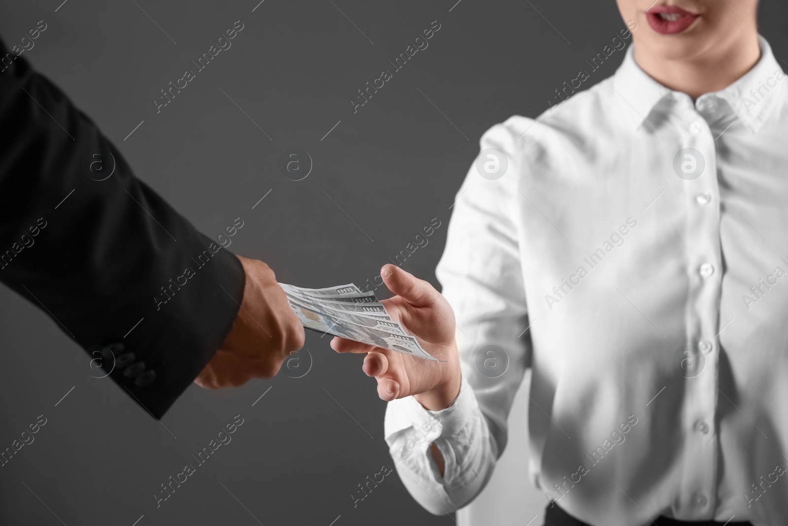 Photo of Man giving bribe money to woman on dark background, closeup