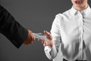 Man giving bribe money to woman on dark background, closeup