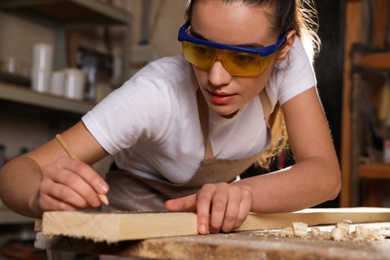 Photo of Professional carpenter measuring wooden board in workshop