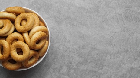 Photo of Bowl of tasty dry bagels (sushki) on grey table, top view. Space for text