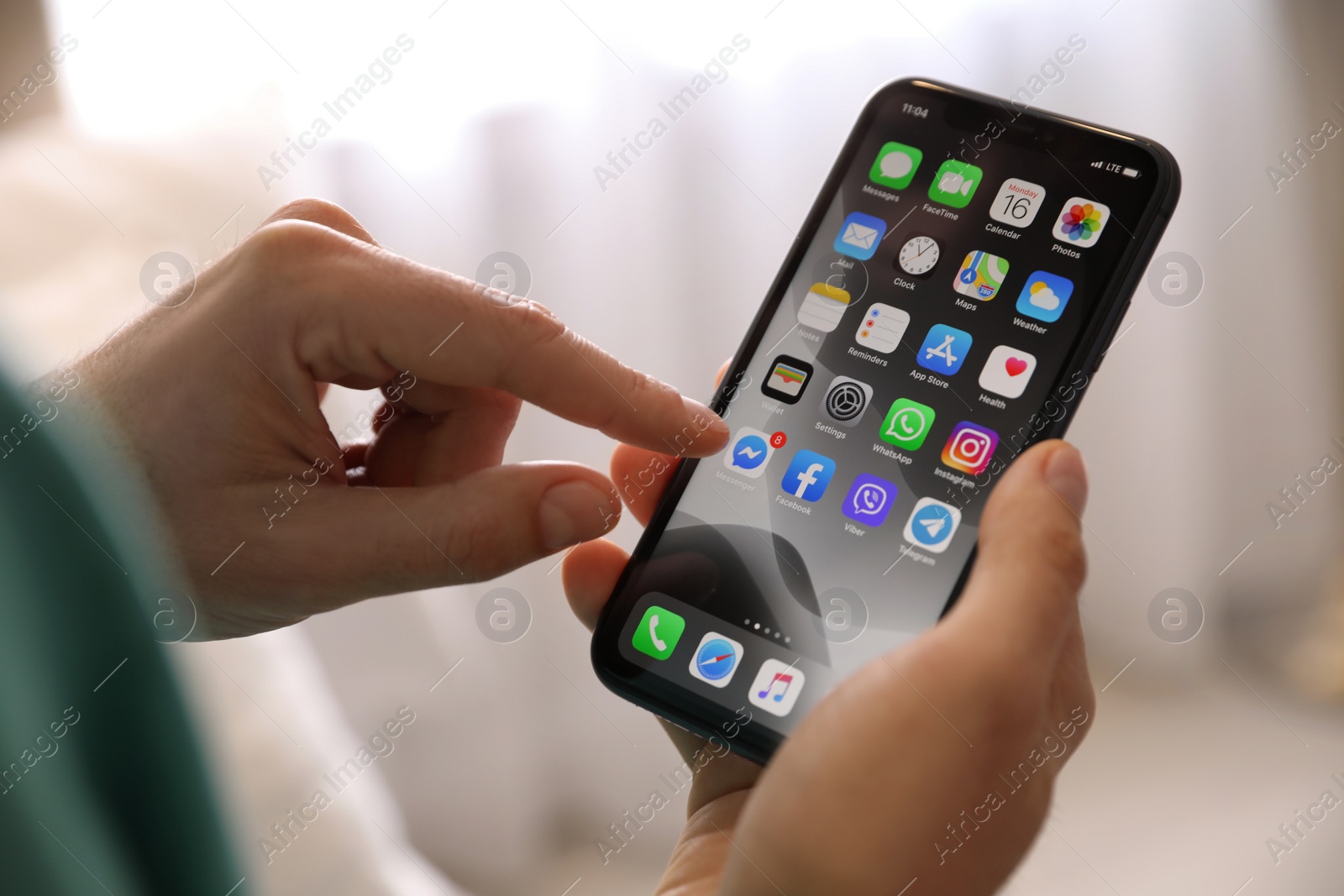 Photo of MYKOLAIV, UKRAINE - MARCH 16, 2020: Man holding iPhone 11 with home screen indoors, closeup