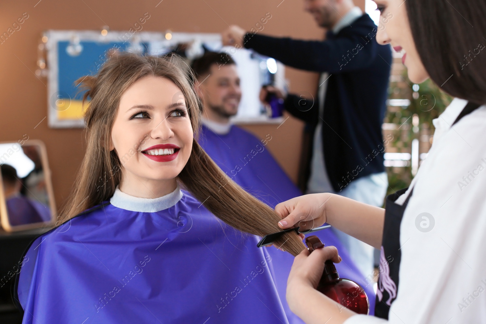 Photo of Professional hairdresser working with client in beauty salon