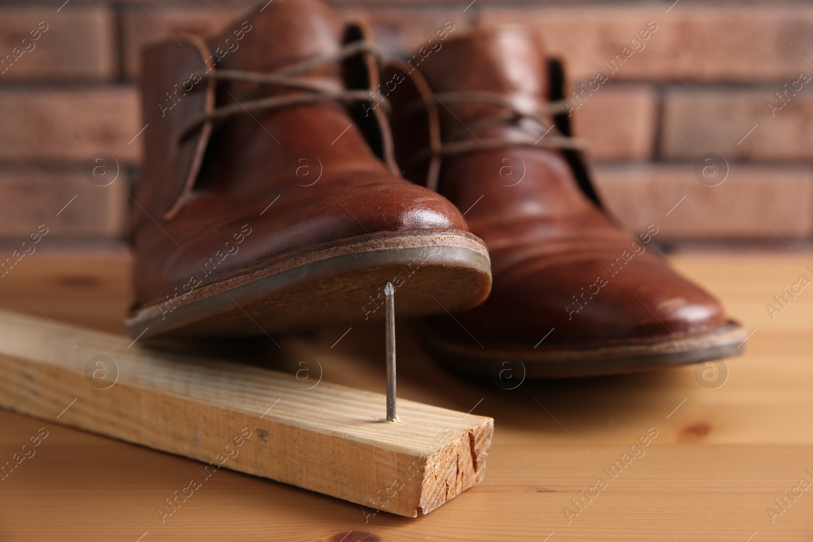 Photo of Metal nail in wooden plank and shoes on table