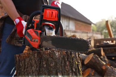 Photo of Man sawing wooden log outdoors, closeup view