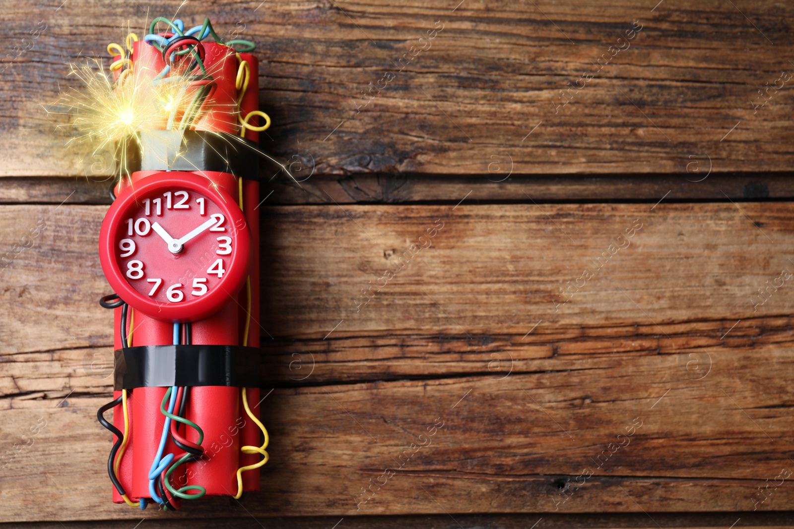 Image of Dynamite time bomb with burning wires on wooden table, top view. Space for text