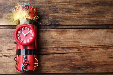 Dynamite time bomb with burning wires on wooden table, top view. Space for text