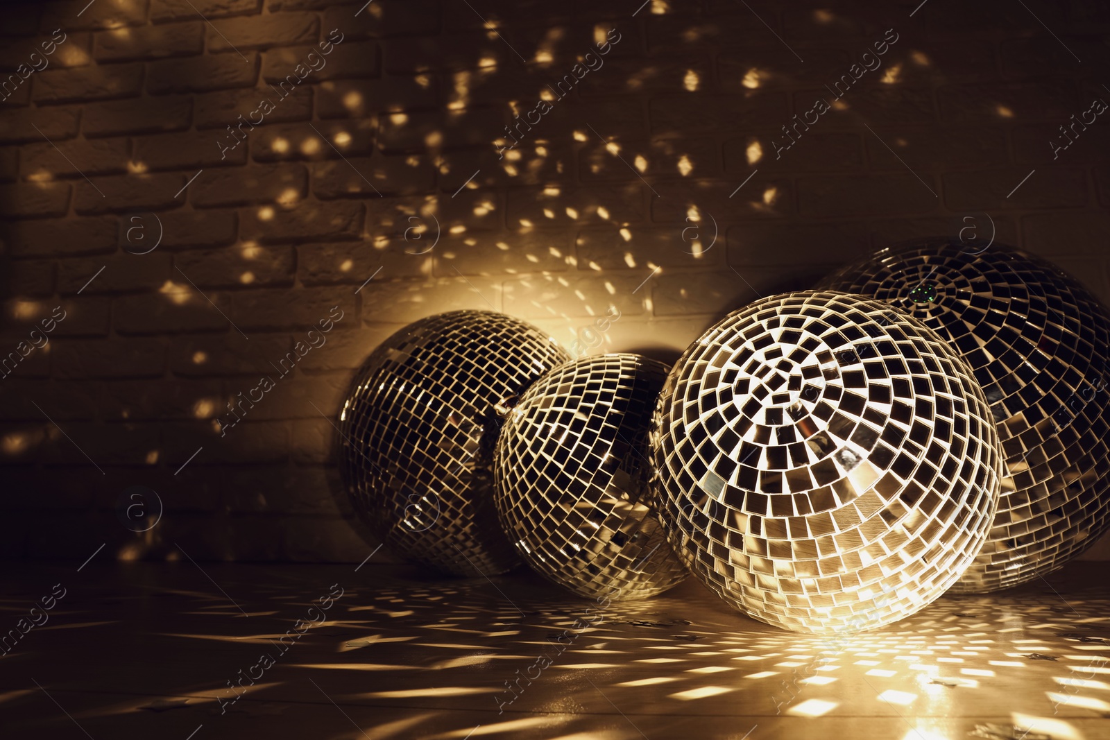 Photo of Many shiny disco balls near brick wall indoors, color toned. Space for text