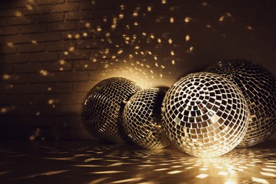 Photo of Many shiny disco balls near brick wall indoors, color toned. Space for text