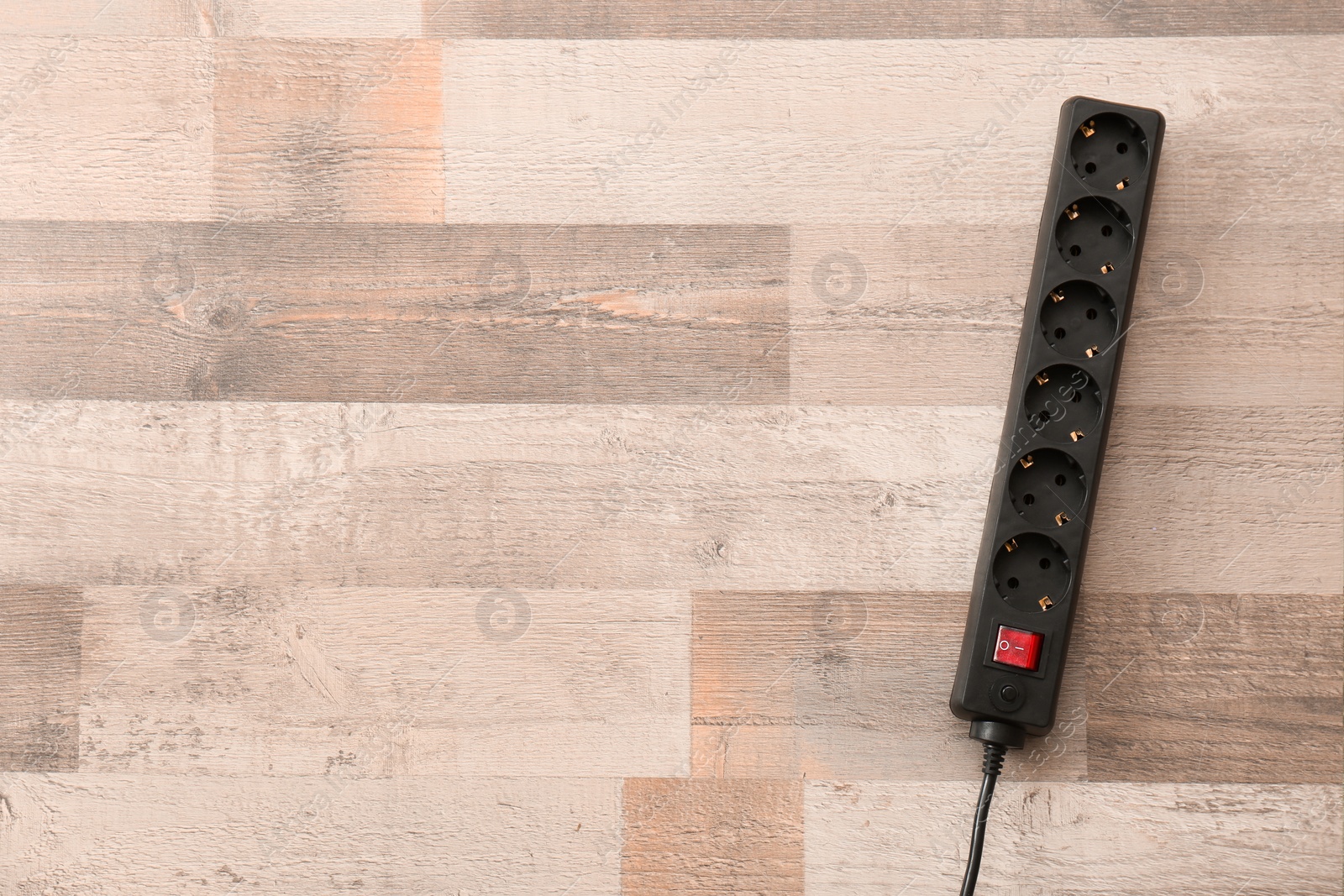 Photo of Extension cord on wooden floor, top view with space for text. Electrician's equipment