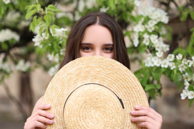 Photo of Beautiful woman with straw hat near blossoming tree on spring day