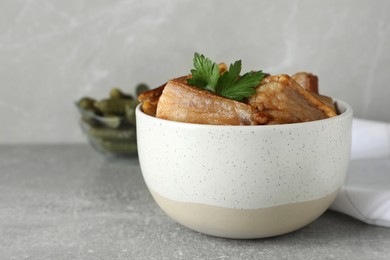 Photo of Bowl with tasty fried pork fatback slices on light grey table, space for text