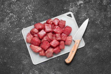 Cooking delicious goulash. Raw beef meat and knife on grey textured table, top view