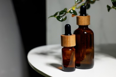 Glass bottles of essential oil on white table, space for text