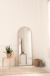 Photo of Beautiful mirror and plants near white wall indoors. Interior design