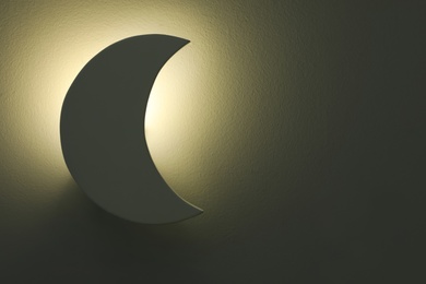 Photo of Crescent shaped night lamp on wall. Space for text