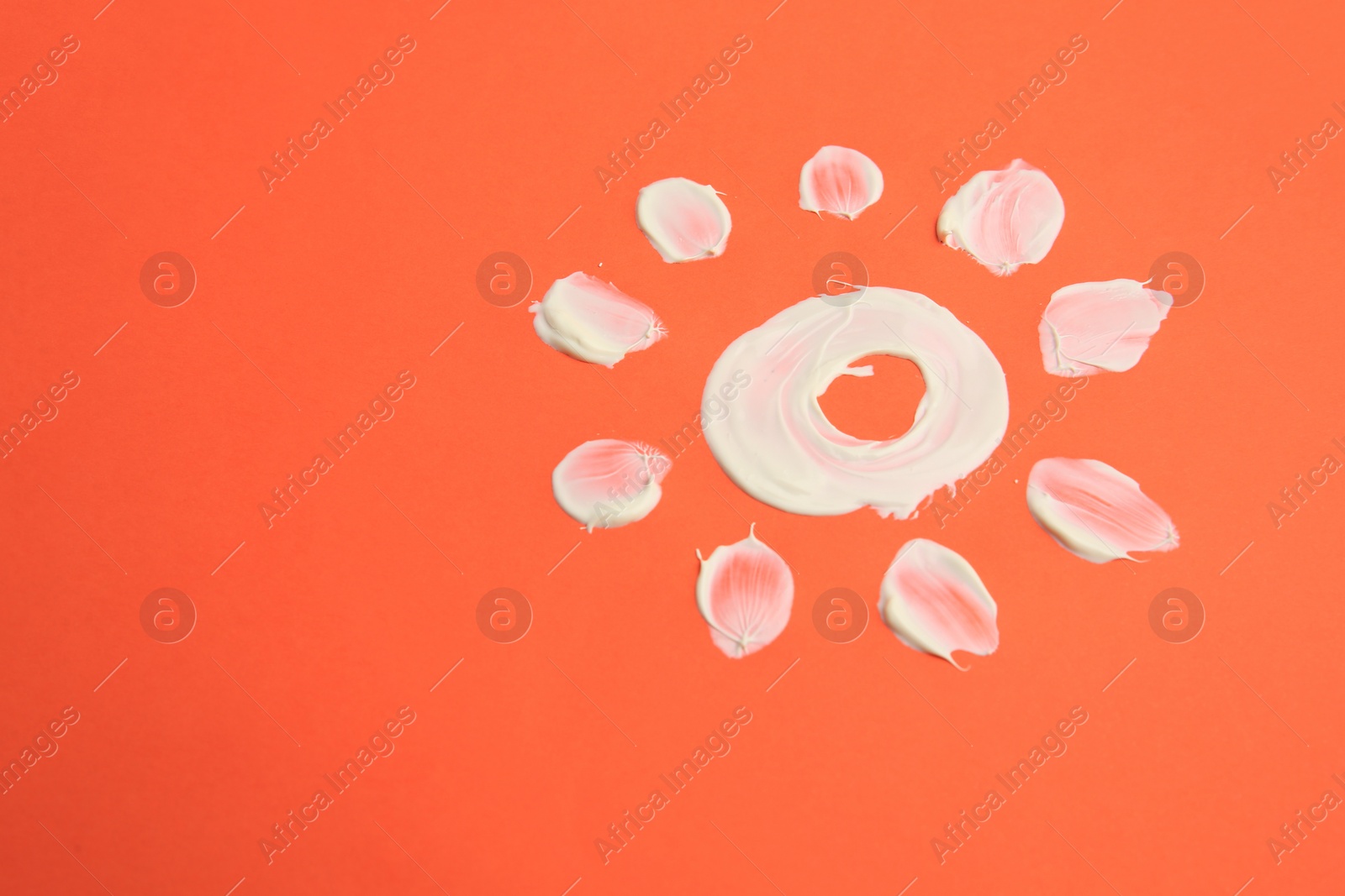 Photo of Drawing of sun with cream on coral background, space for text. Skin care and protection