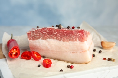 Photo of Composition with pork fatback and spices on board against blue background