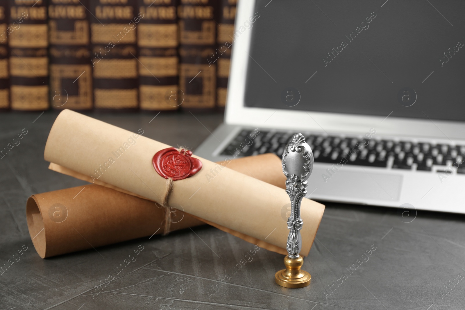 Photo of Notary's public pen and sealed documents near laptop on grey stone table