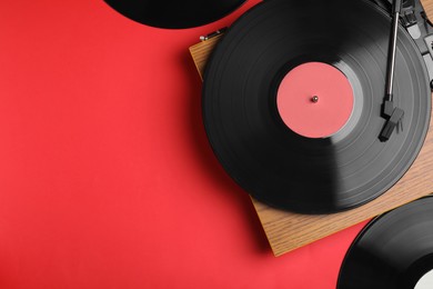 Photo of Modern player and vinyl records on red background, flat lay. Space for text