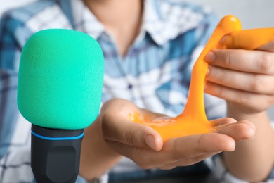 Photo of Woman making ASMR sounds with microphone and bright slime, closeup