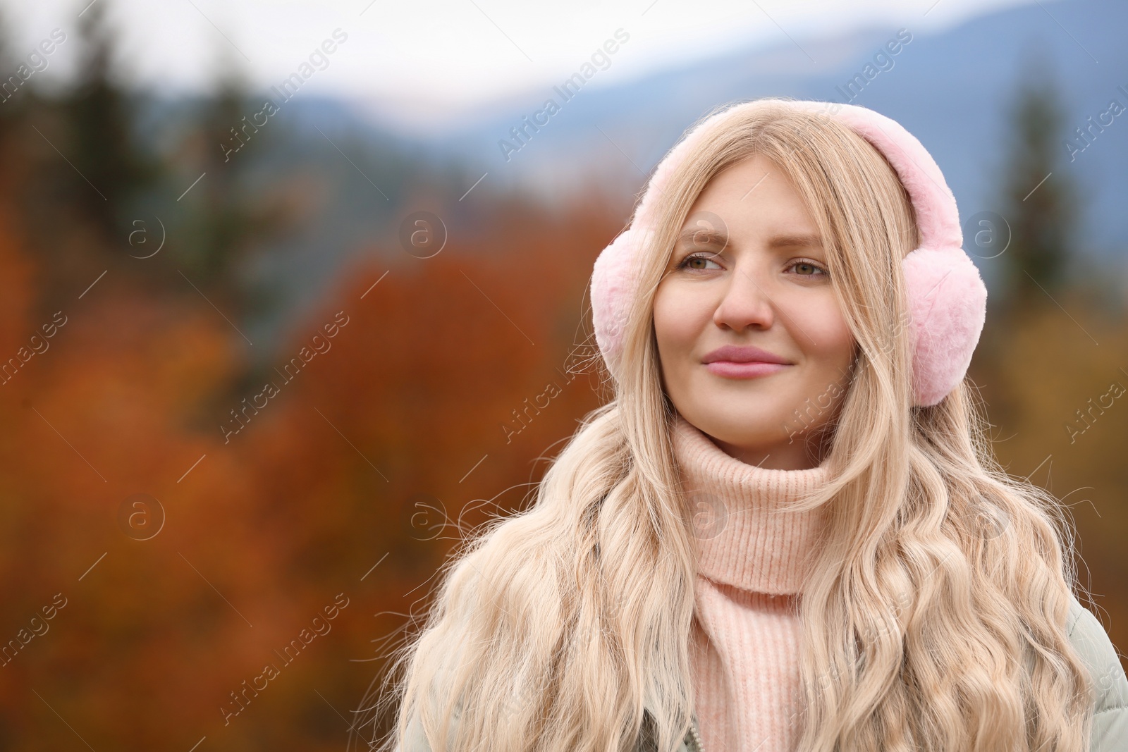 Photo of Young beautiful woman wearing warm earmuffs in mountains