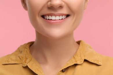 Woman with clean teeth smiling on pink background, closeup