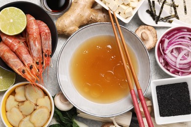 Cooking delicious ramen soup. Different fresh ingredients in bowls and chopsticks on table, flat lay