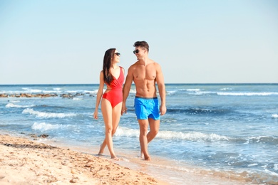 Happy young couple walking together on beach