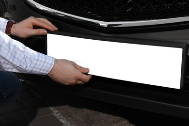 Photo of Man installing vehicle registration plate outdoors, closeup. Mockup for design