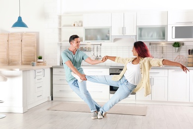 Beautiful couple dancing in kitchen at home