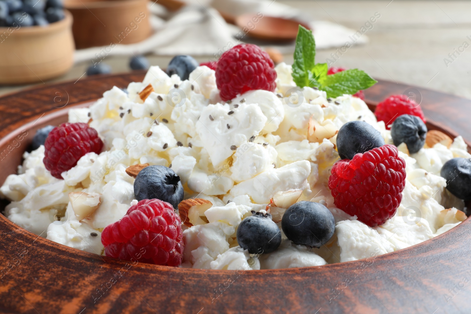 Photo of Fresh cottage cheese with berries and mint in plate, closeup