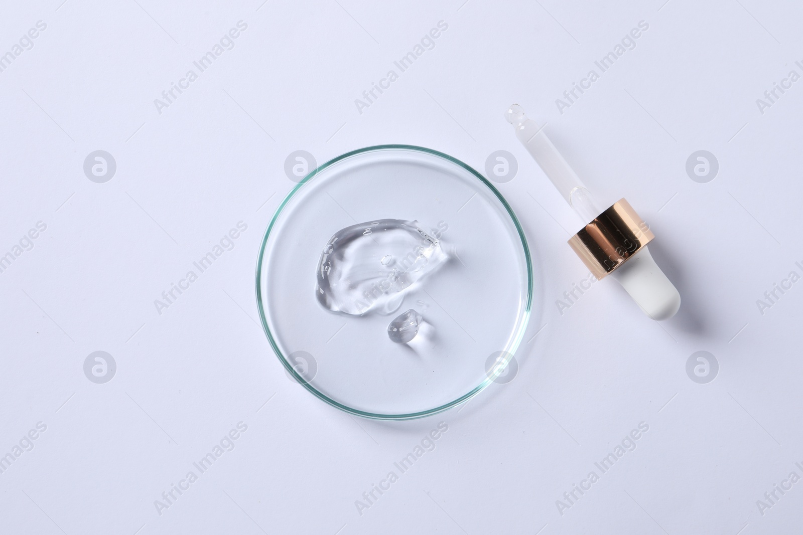 Photo of Petri dish with cosmetic serum and pipette on white background, flat lay